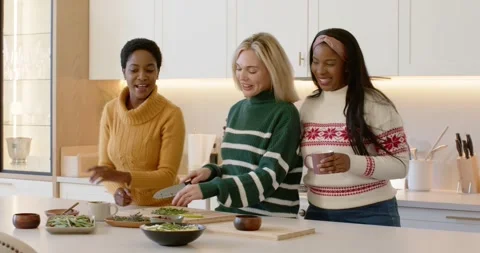 Diverse female friends heeding left woman's pointing, chopping salad into bowls Stockbeeldmateriaal 345589507