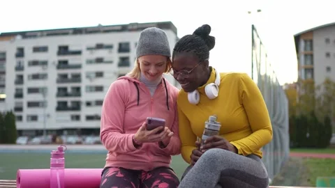 Diverse female friends laughing while using a smartphone after training Stock Footage 321944357