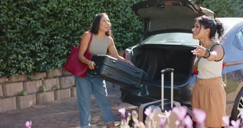 Diverse female friends pulling black suitcase after trunk opening while pointing Stock Footage 336368417