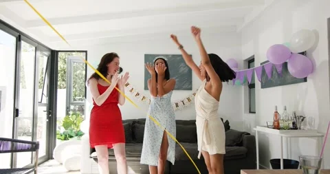 Diverse female friends pulling party poppers on cue in living room, sending Stock Footage 317084047