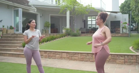 Diverse female friends talking in backyard showing arm stretch while warming up Vidéo 343367398