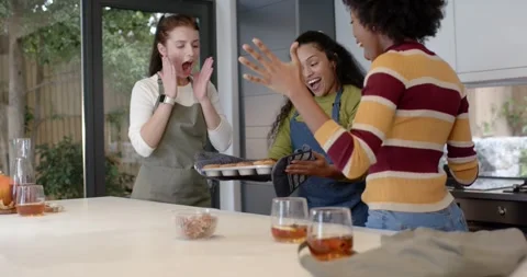 Diverse female friends timer beeping opening oven lifting tray with mitts Stock Footage 340655279