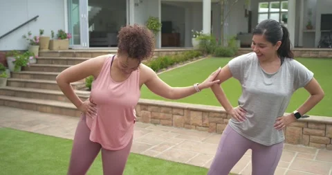 Diverse female friends warming up with bands on purple mats in backyard, Stock Footage 340974053