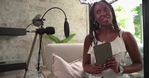 Diverse female host holding tablet, reading prompts, speaking into mic, guest Stock Footage 341665315