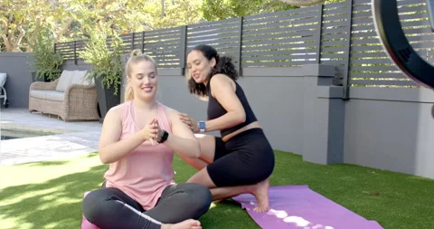 Diverse female instructor guiding client stretching and correcting posture on Stock Footage 313955612