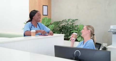 Diverse female nurses talking at desk, standing leaning, wearing stethoscope, Stock Footage 335683269
