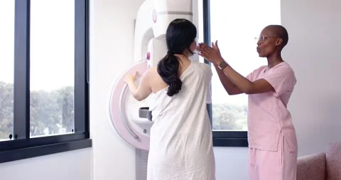 Diverse female patient and tech following gestures positioning in gown for Stock Footage 337705352