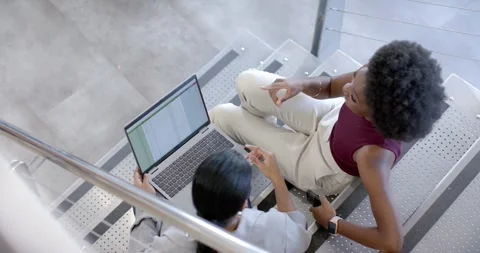 Diverse female peers seeing table on laptop at stairs with phone pointing Stock Footage 342066610