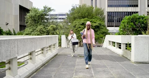 Diverse female students from bridge end walking to class, pink hoodie checking 스톡 동영상 344330736