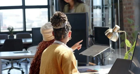 Diverse female team collaborating on coding project in modern office, discussing Stock Footage 311495437