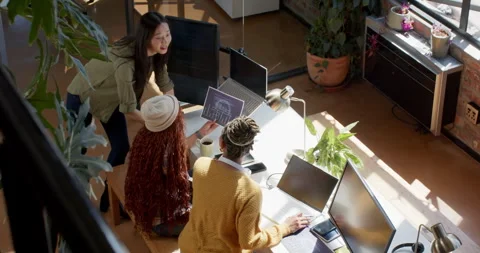Diverse female team collaborating on coding project in modern office with Stock Footage 311495450