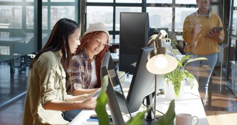 Diverse female team collaborating on coding project in modern office, using Stock Footage 311495474