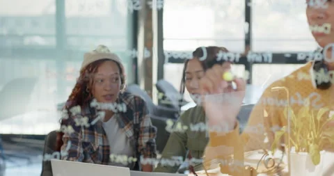 Diverse female team collaborating on coding project, writing on glass board in Stock Footage 311495480