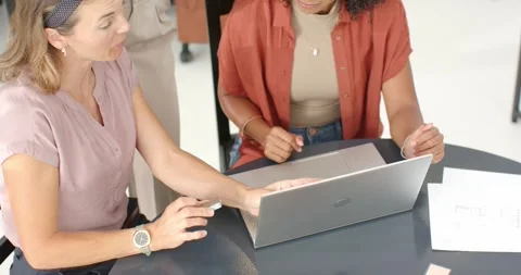 Diverse female team at round table, standing woman leaning, pointing with pen Stock Footage 340974484