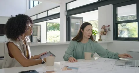 Diverse female team in studio right flipping plans left using tablet and laptop 库存影片 344331537