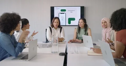 Diverse female team in work attire watching wall monitor showing app mockup, Stock Footage 342996052