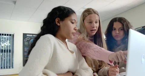 Diverse female teens working on assignment at laptop, lead teen pointing, Stock Footage 340656015
