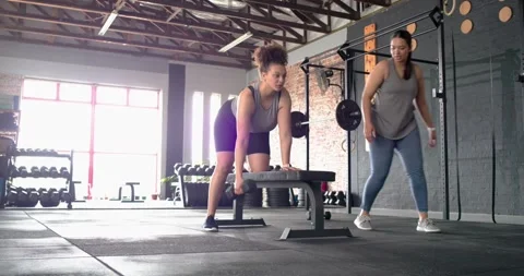 Diverse female trainer clapping and counting reps on stopwatch while client Video stock 344224669