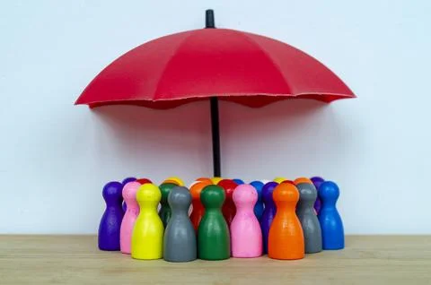 Diverse figures protected under red umbrellas representing inclusive leader.. Stock Photos