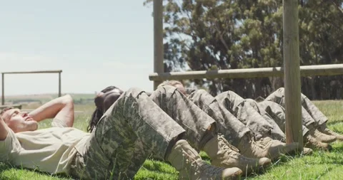 Diverse fit group of soldiers doing sit ups in field, at army obstacle course in Stock Footage 336534289