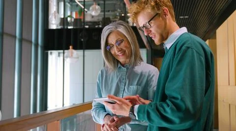 Diverse friendly coworkers talking using digital tablet, discussing project. Stock Photos