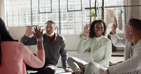 Diverse friends in activewear after class in loft, raising hands and exchanging Stock Footage 337255313