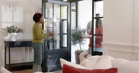 Diverse friends arriving, host opening glass door, guest holding foil dish, dog Stock Footage 344456783