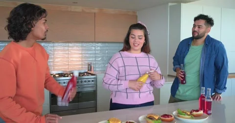 Diverse friends assembling burgers for meal prep after ketchup squeeze, shaking Stock Footage 344534871
