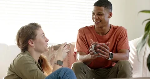 Diverse friends chatting on couch in bright living room, man speaking, woman Stock Footage 341664957