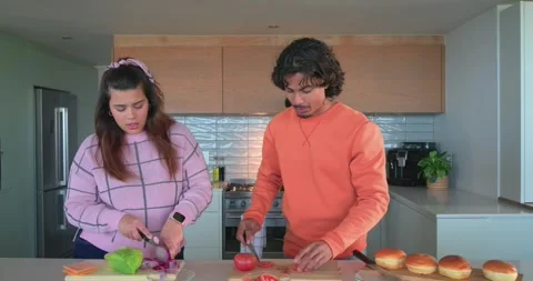 Diverse friends chopping veggies, preheating stove and oiling pans in kitchen Stock Footage 341089729