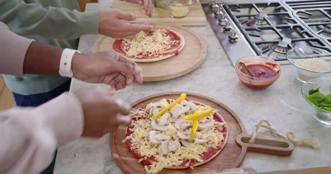 Diverse friends deciding dinner, assembling pizzas at kitchen counter using Stock Footage 346614289