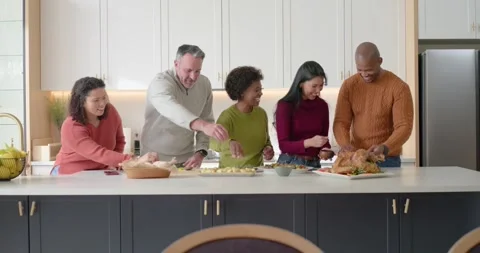 Diverse friends gathering around kitchen island, preparing dinner with turkey, Stock Footage 344402591