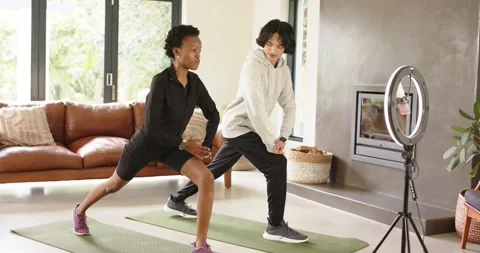 Diverse friends glancing toward ring light stepping into side lunge at home to Stock Footage 343366421