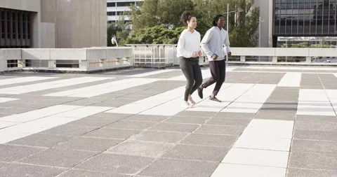 Diverse friends jogging, walking on rooftop terrace tiles by railing catching Stock Footage 317788044