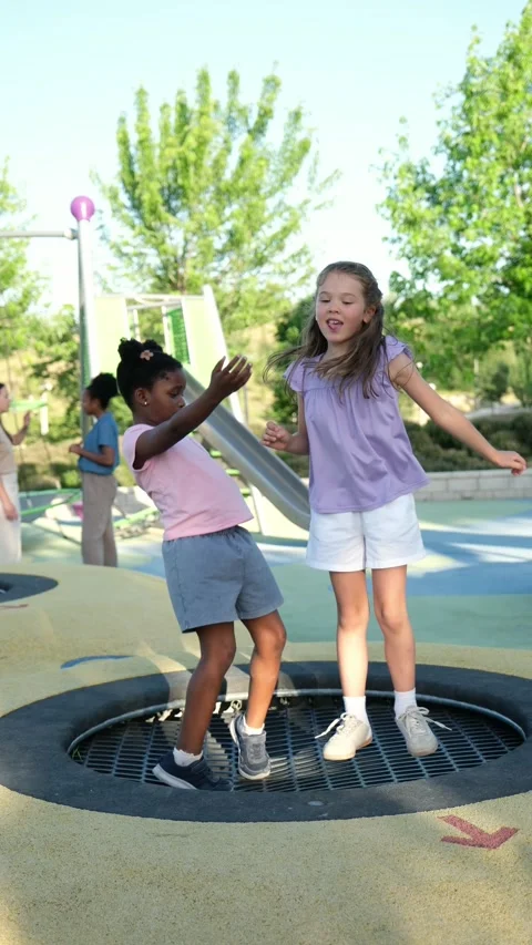 Diverse friends jumping together on a playground trampoline Stock Footage 341801962