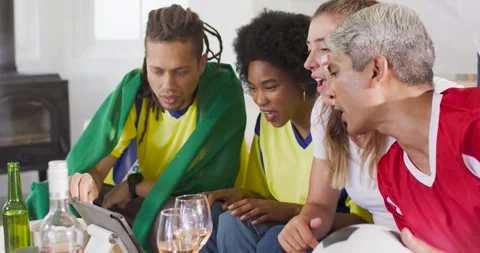 Diverse friends leaning forward watching football match on tablet, pointing, Stock Footage 340011717