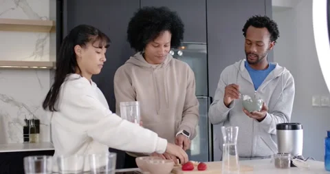 Diverse friends making smoothie at kitchen island, ring light signaling, adding Stock Footage 345590194