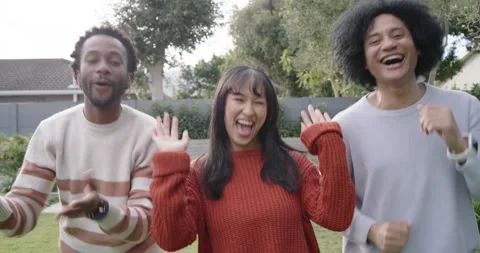 Diverse friends moving to off-camera beat in backyard, stepping and raising Stock Footage 344656675