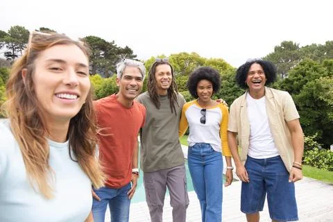 Diverse friends posing for selfie on backyard pool deck, laughing and showing 스톡 사진