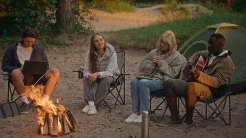 Diverse Friends Sitting by Campfire on Beach Playing Guitar Stock Footage 343256954