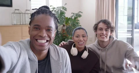 Diverse friends sitting on couch, left friend reaching for camera, recording and Stock Footage 346614337