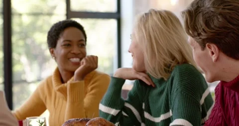 Diverse friends sitting at table with roasted turkey, blond woman leaning, Stock Footage 344230523