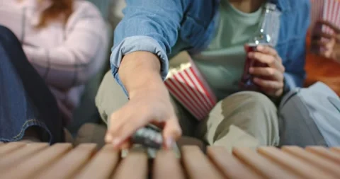 Diverse friends on sofa watching TV pressing remote button, sliding across table Stock Footage 339272047