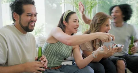 Diverse friends starting game on sofa beside glass wall, holding white Stock Footage 337098563