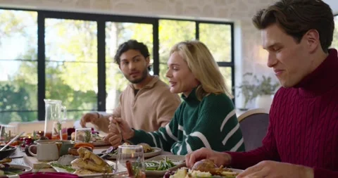 Diverse friends in sweaters at table, plates being set out, eating, toasting Stock Footage 344460543