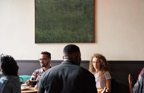 Diverse friends talking together while sitting in a cafe Stock Photos