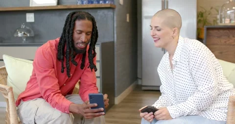 Diverse friends tapping and scrolling smartphones at coffee table, leaning in, Stock Footage 340454328