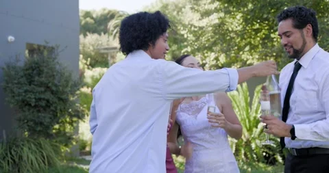 Diverse friends toasting in backyard after woman in white raising arms and Stock Footage 345037299