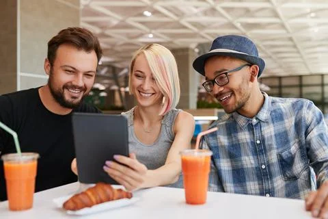 Diverse friends using tablet in restaurant Stock Photos