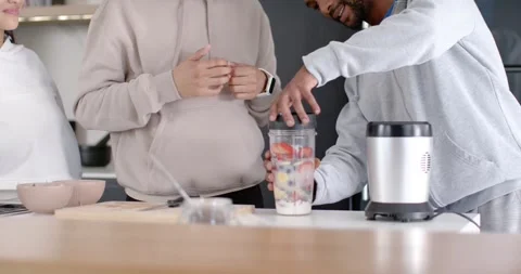 Diverse friends watching right-side man filling and locking personal blender cup Stock Footage 345590117